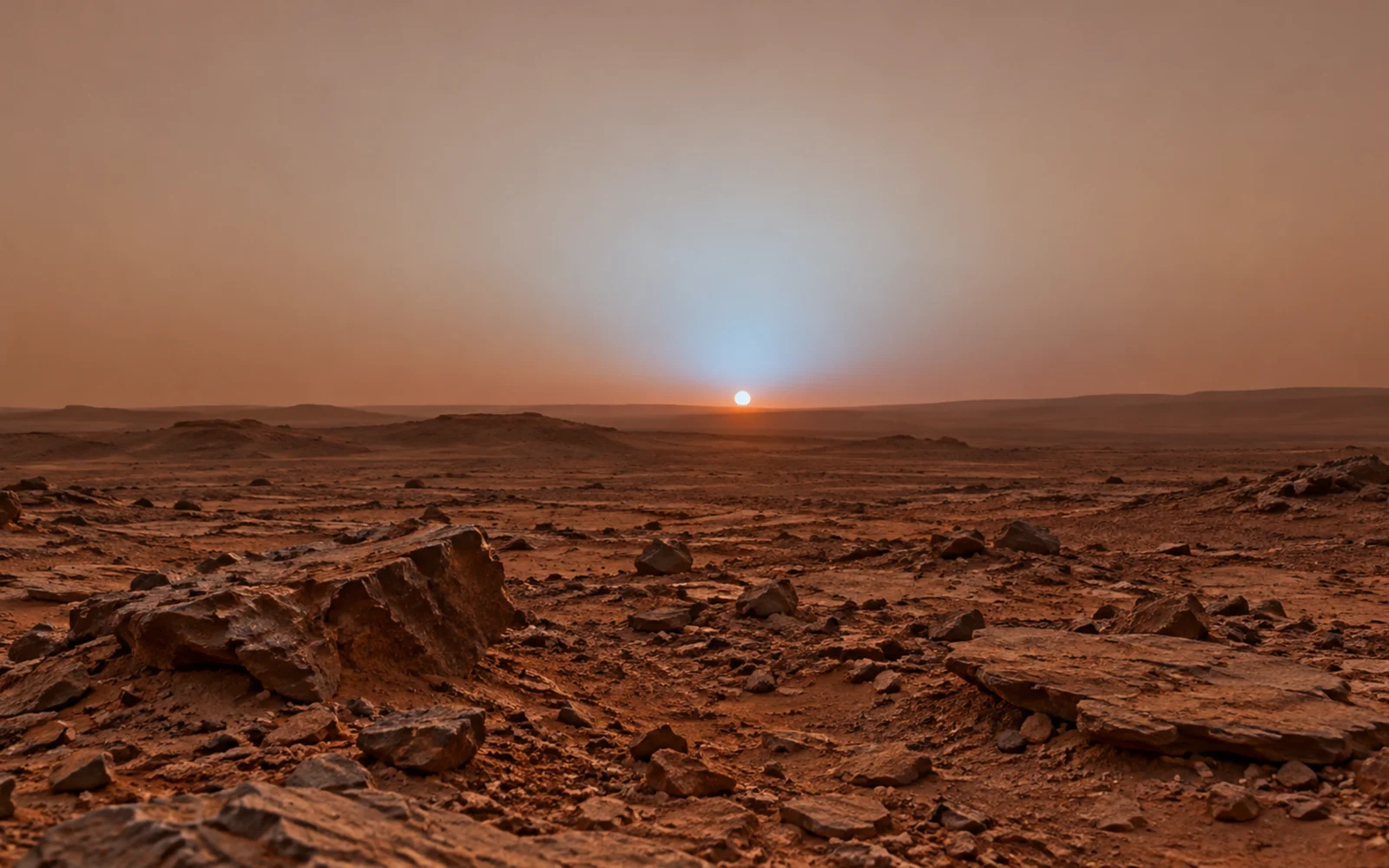Paisaje rocoso marciano con un halo azul localizado alrededor del Sol al atardecer.